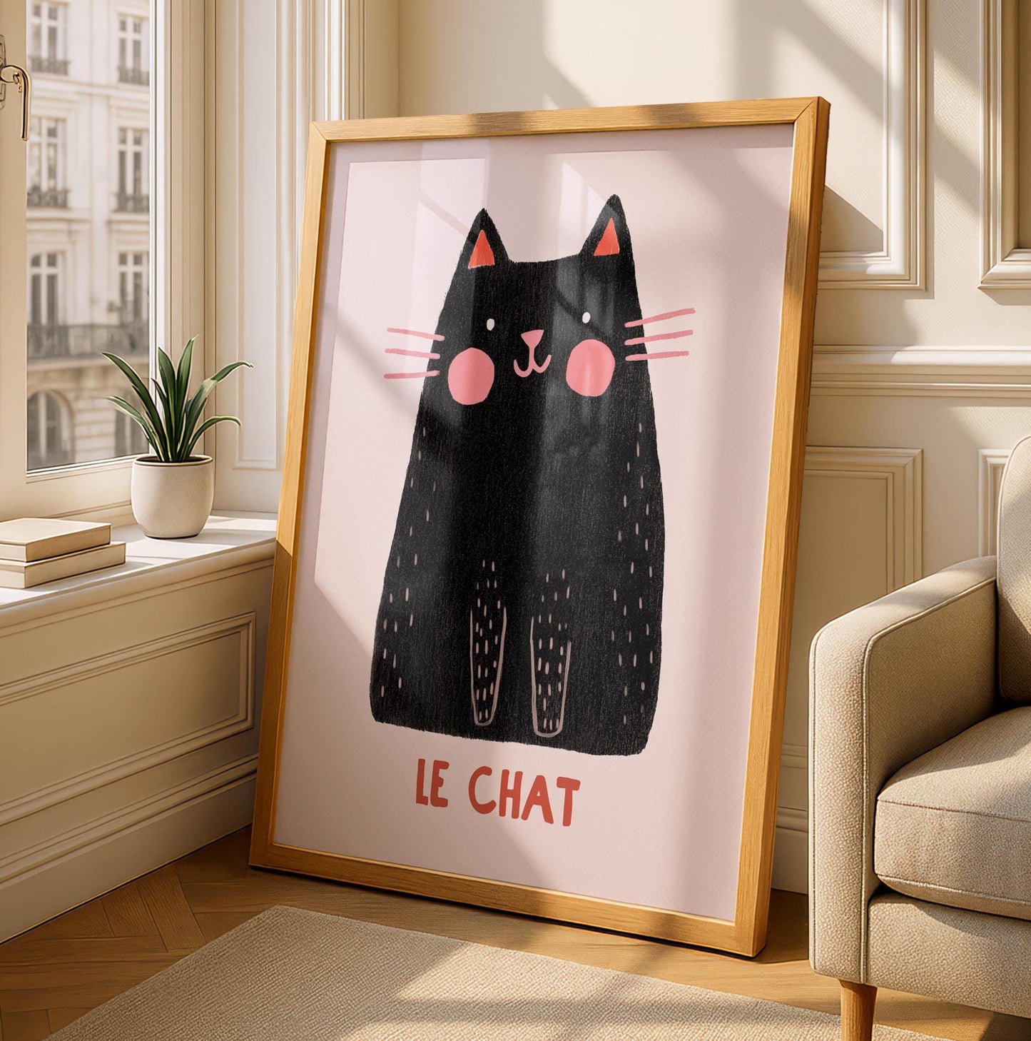 A framed print of a black cat with pink cheeks and ears, and the words "LE CHAT" in red, leans against a wall next to a window.