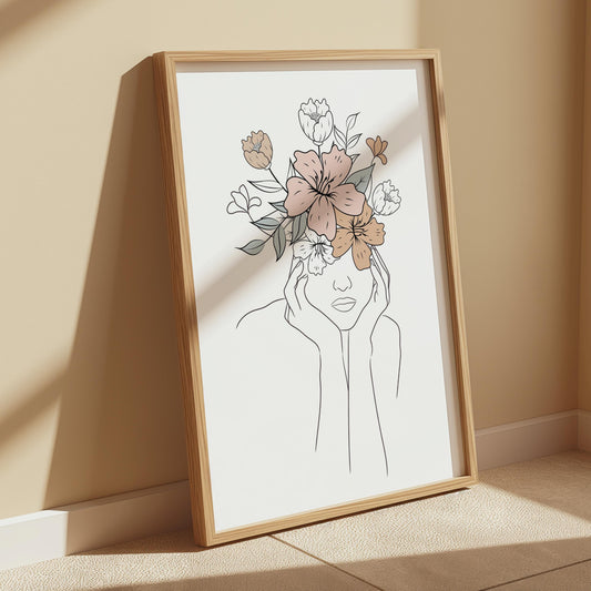 A framed line art print of a woman's head and shoulders with flowers instead of hair, leaning against a beige wall.